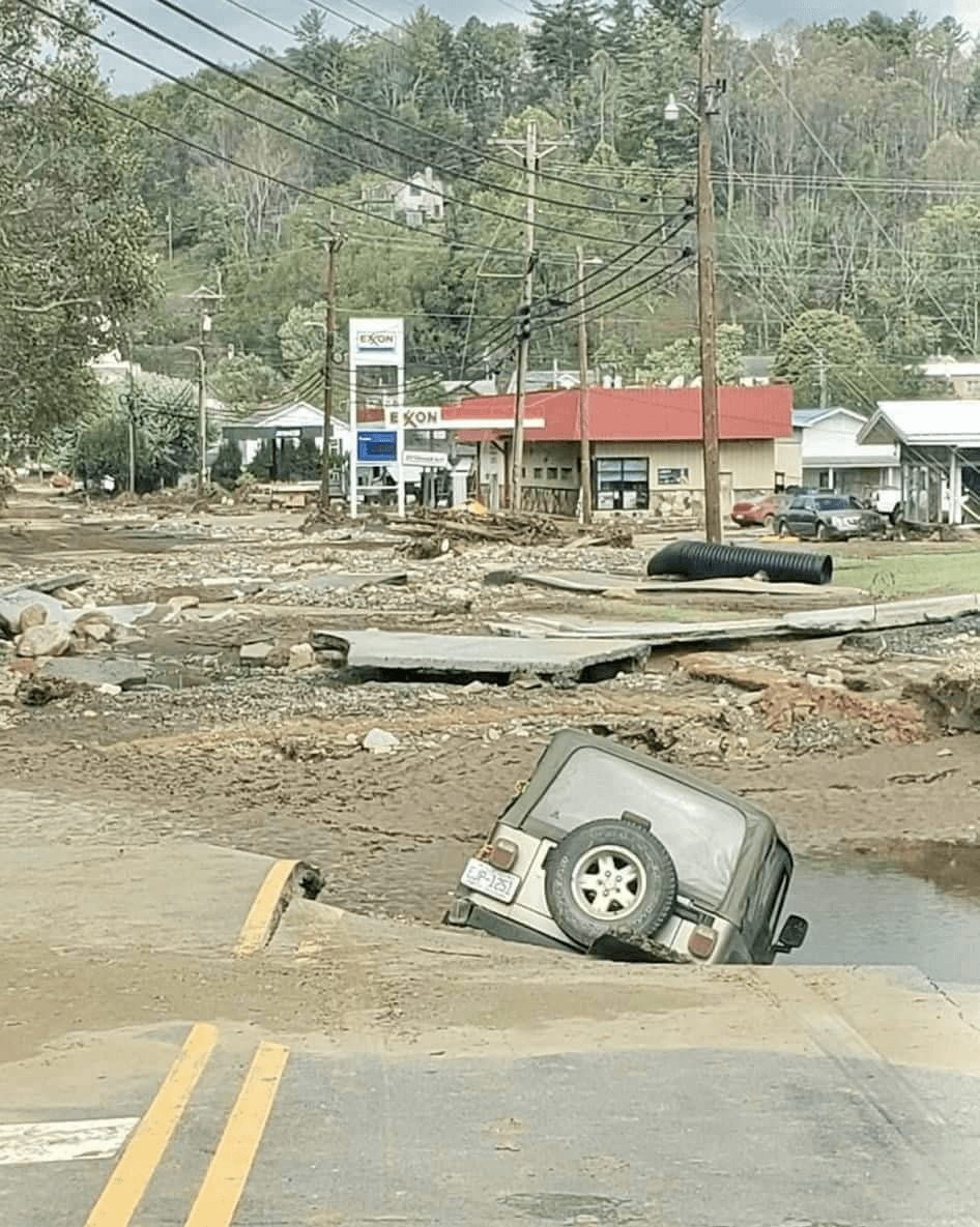 A vehicle and roadway damaged by floodwater